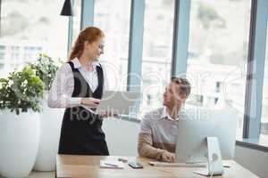 Smiling executives interacting while working at desk