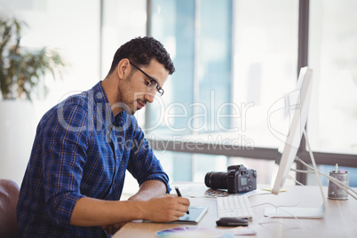 Graphic designer using graphic tablet at desk
