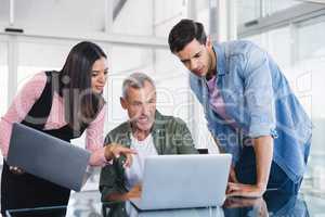 Business people discussing over laptops