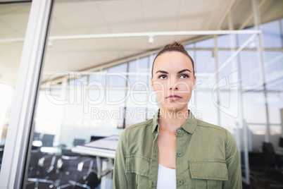 Thought businesswoman against glass wall