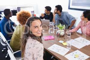 Portrait of businesswoman sitting with colleagues in meeting