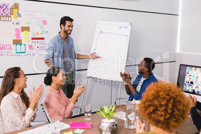 Cheerful colleagues applauding at businessman explaining