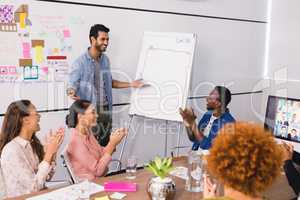 Cheerful colleagues applauding at businessman explaining