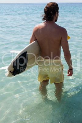Surfer with surfboard looking at sea