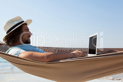 Man using laptop while relaxing on hammock