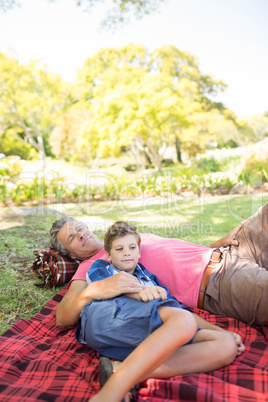 Father and son lying on picnic blanket in park