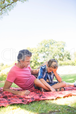 Father consoling his son at picnic in park