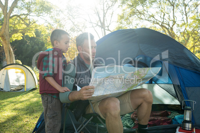 Father and son looking at map outside the tent