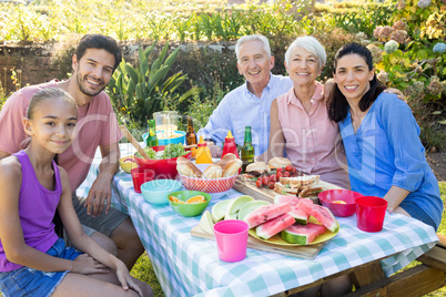 Family smiling at camera while having meal outdoors