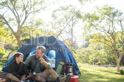 Father and son holding a fishing rod outside the tent