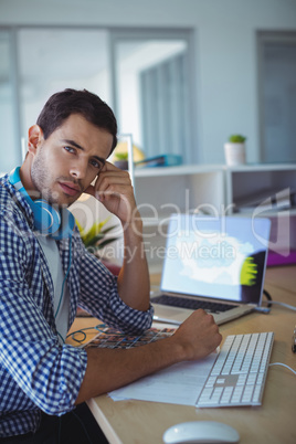Thoughtful graphic designer sitting in creative office