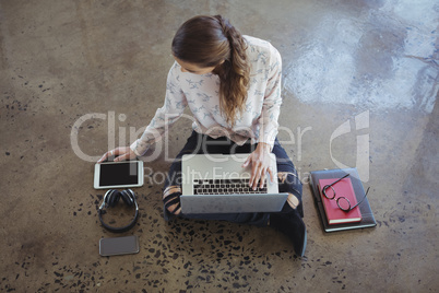 Businesswoman working with laptop and digital tablet on floor
