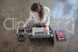 Businesswoman working with laptop and digital tablet on floor