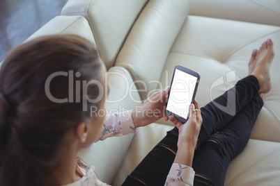 High angle view of businesswoman holding mobile phone while resting on sofa