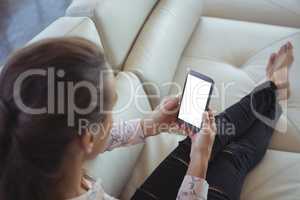 High angle view of businesswoman holding mobile phone while resting on sofa