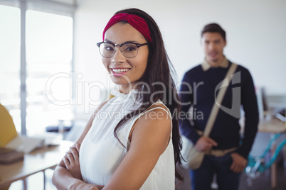 Smiling young businesswoman standing with male colleague in background