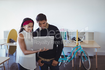 Young business colleagues using laptop at office