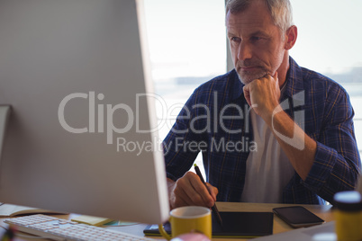 Focused businessman working on digitizer at office desk