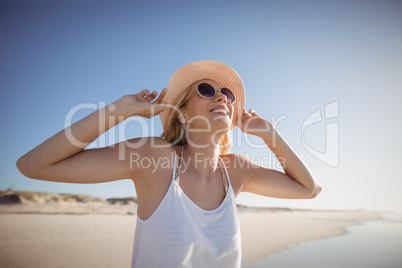 Happy woman wearing sunglasses and hat at beach