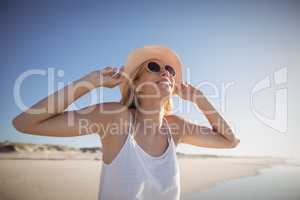 Happy woman wearing sunglasses and hat at beach