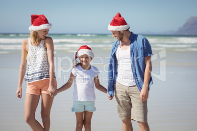 Happy family wearing Santa hat while standing at beach