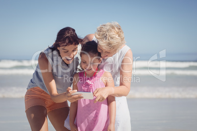 Happy multi-generation family using mobile phone at beach