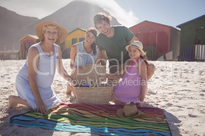 Portrait of happy multi-generation family by picnic blanket at beach