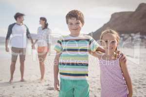 Portrait of smiling siblings with parents standing in backgeround