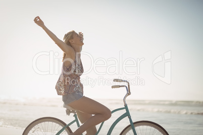 Side view of cheerful woman riding bicycle at beach