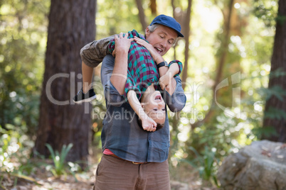 Father carrying little son while hiking in forest