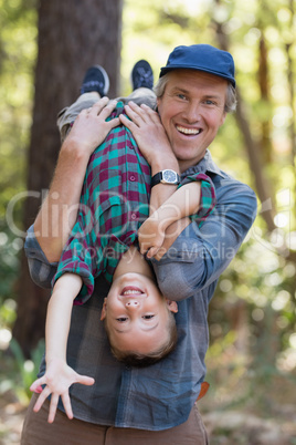 Playful father carrying son while hiking in forest