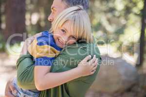 Smiling boy embracing father in forest