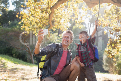 Father taking selfie with son in forest