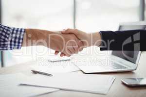 Close-up of executives shaking hands at desk