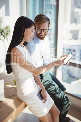 Happy executives using mobile phone at desk