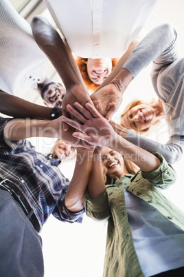 Directly below portrait of smiling business people stacking hands
