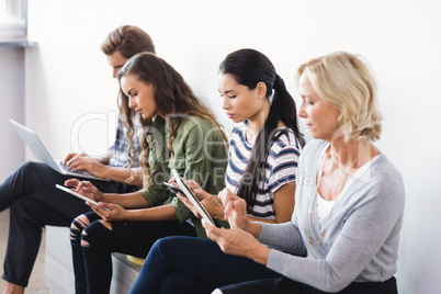 Business people using technologies while sitting on seat