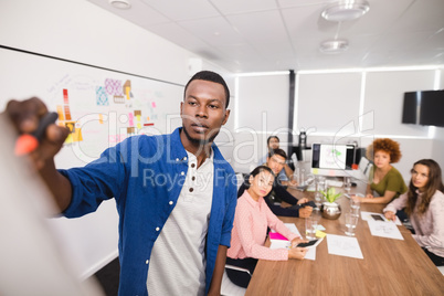 Creative businessman writing on whiteboard during meeting