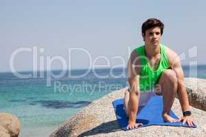 Man performing yoga on rock