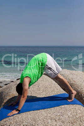Man performing yoga on rock