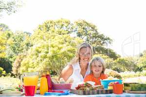 Portrait of happy mother and son having meal in park