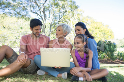 Family talking while using laptop in the park