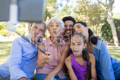 Family making funny faces while taking a selfie in the park