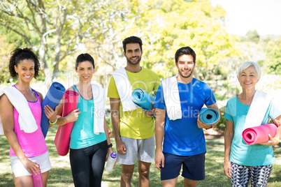 Group of people standing in the park with rolled exercise mats
