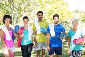 Group of people standing in the park with rolled exercise mats