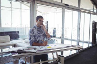 Male interior designer talking on mobile in office