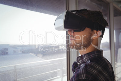 Young businessman wearing vr headset by window in office
