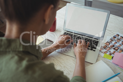 Female photo editor using laptop in creative office