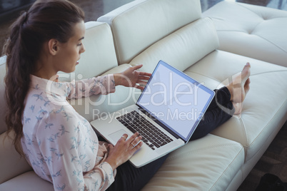 Businesswoman using laptop while resting on sofa