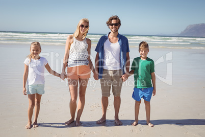Portrait of family holding hands while standing together at beach
